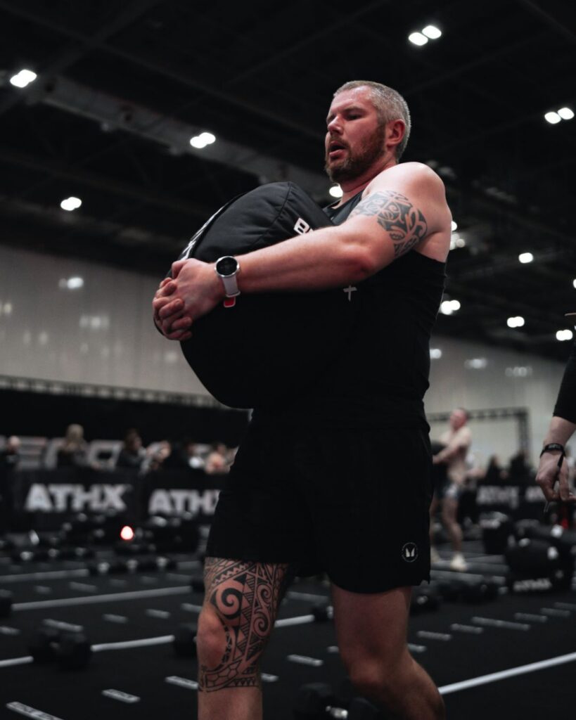 ATHX athlete carrying a sandbag during competition at ATHX London 2026