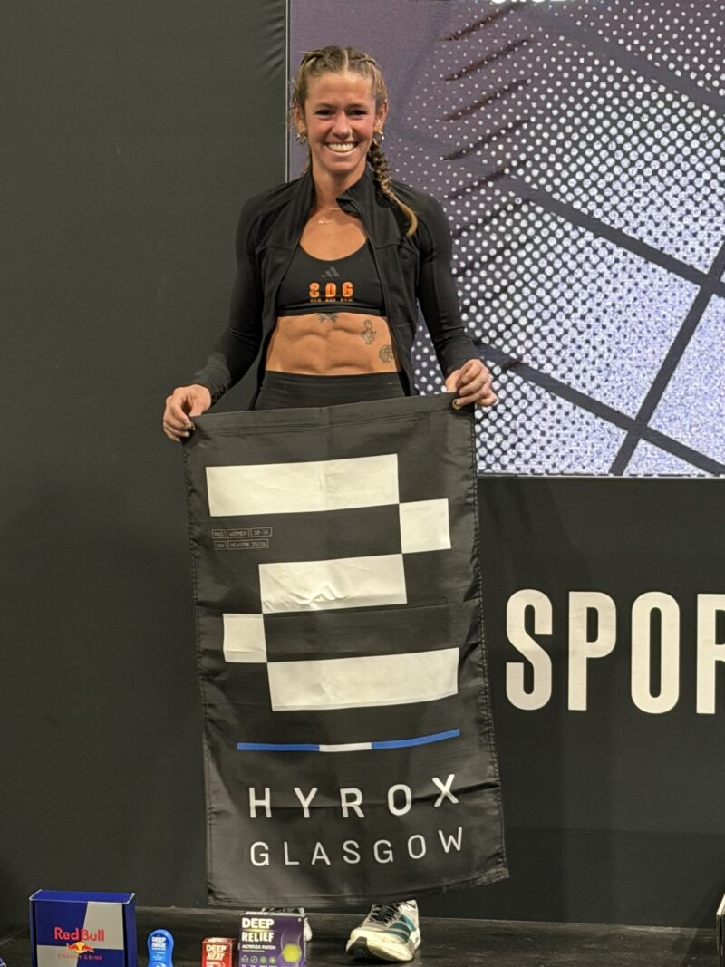 Alyssa McElheny holding HYROX Glasgow flag after finishing third in the Pro Women race