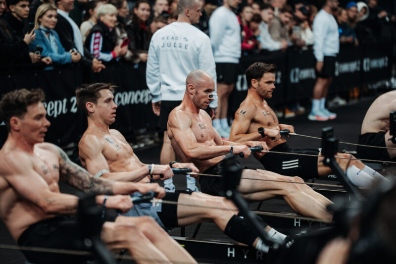 Elite 15 men competing on Concept2 rowing machines at a HYROX Major