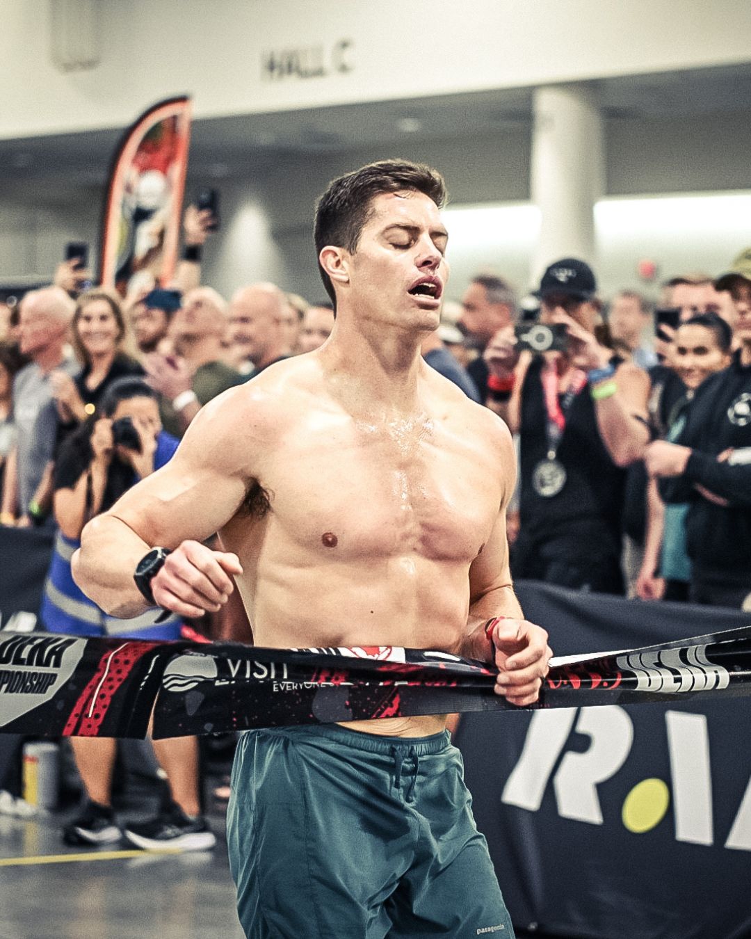 Greyson Kilgore crossing the finish line during a DEKA World Championship race inside a packed indoor venue