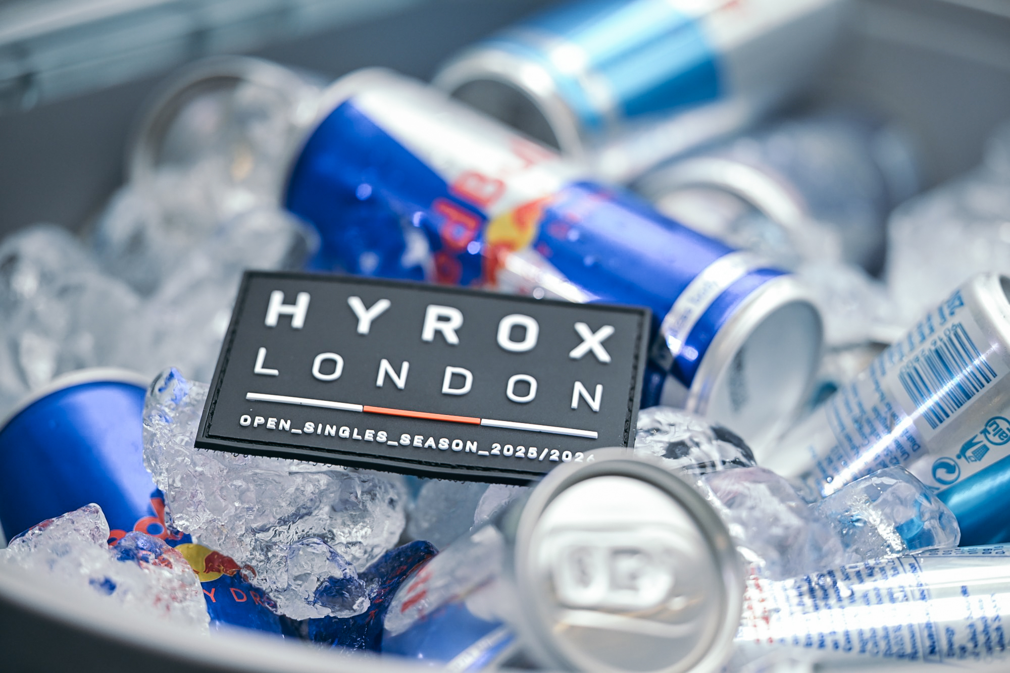 HYROX London event patch on ice with Red Bull cans, representing the HYROX UK Spring 2027 schedule.