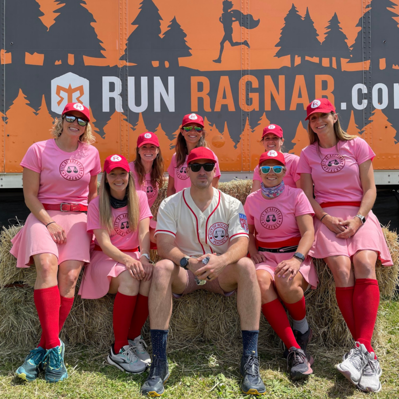 A Ragnar Relay team poses together beneath a “Run Ragnar” banner.